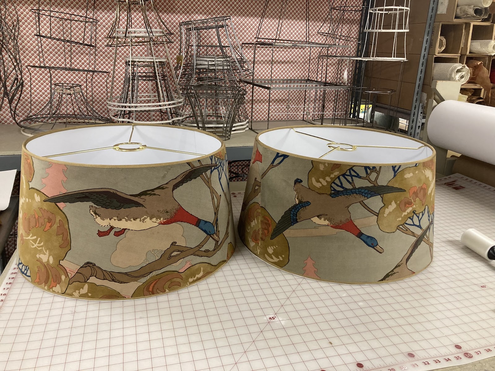 A matched pair of drum shades in a printed duck-and-tree fabric, made in the workroom